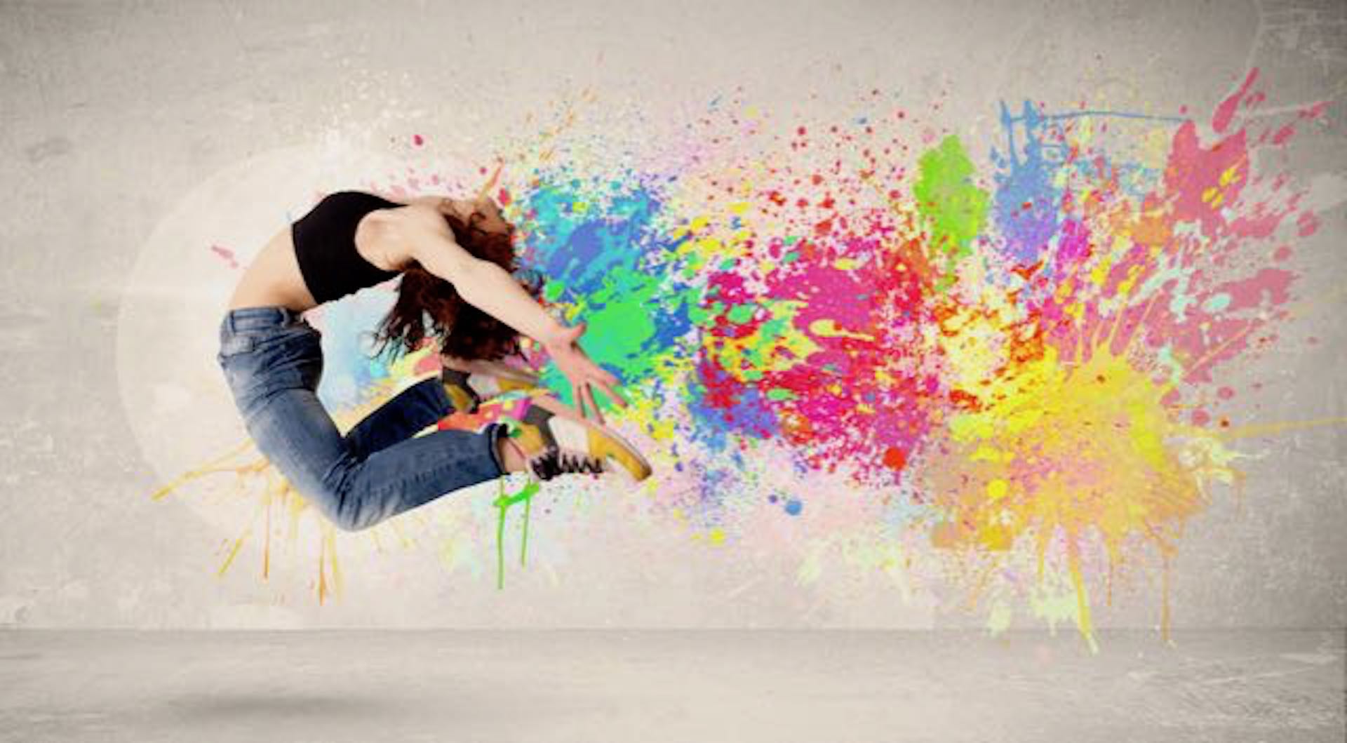 Happy teenager jumping with colorful ink splatter on urban background